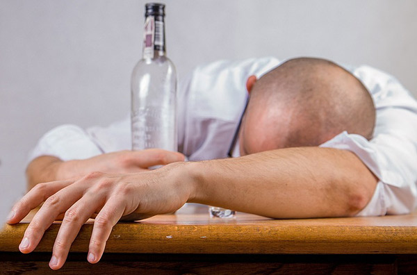 Man sleeping on counter with a bottle of alcohol