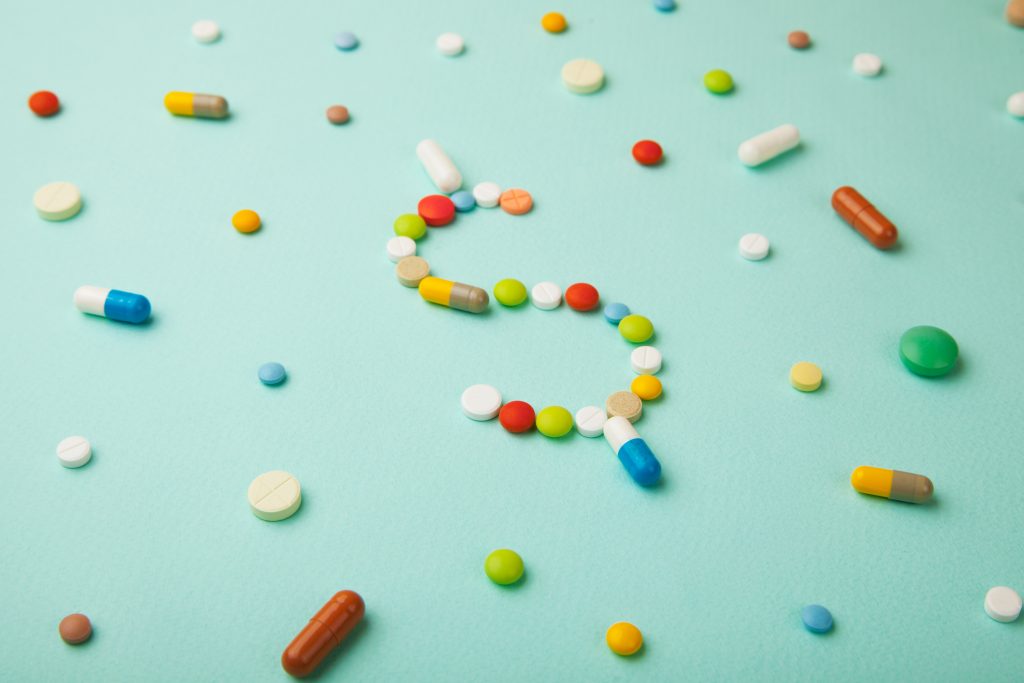 Symbol of money dollar from colored pills and capsules on green background. Expensive medicine and medical insurance