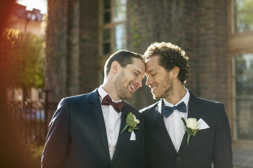 Happy newlywed gay couple standing outdoors