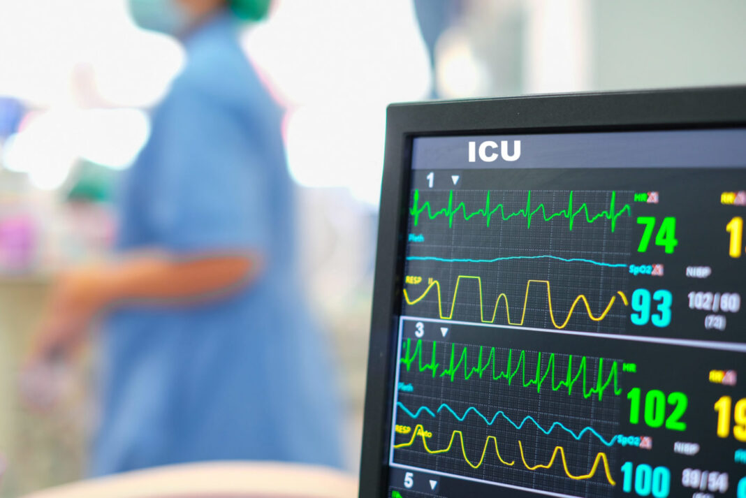 Heart rate monitor, patient and doctors in background in intensive care unit or emergency room