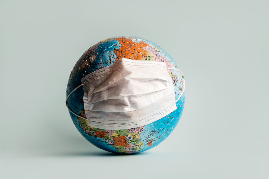 Globe made of jigsaw puzzles with a protective medical mask