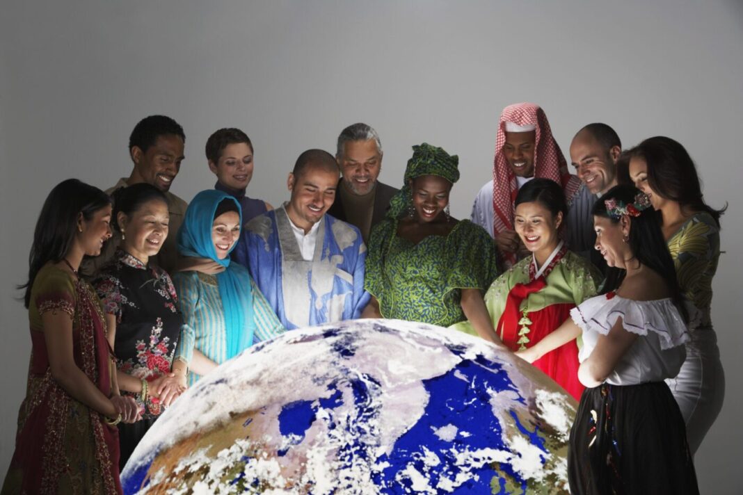 Multi-ethnic people in traditional dress looking at globe