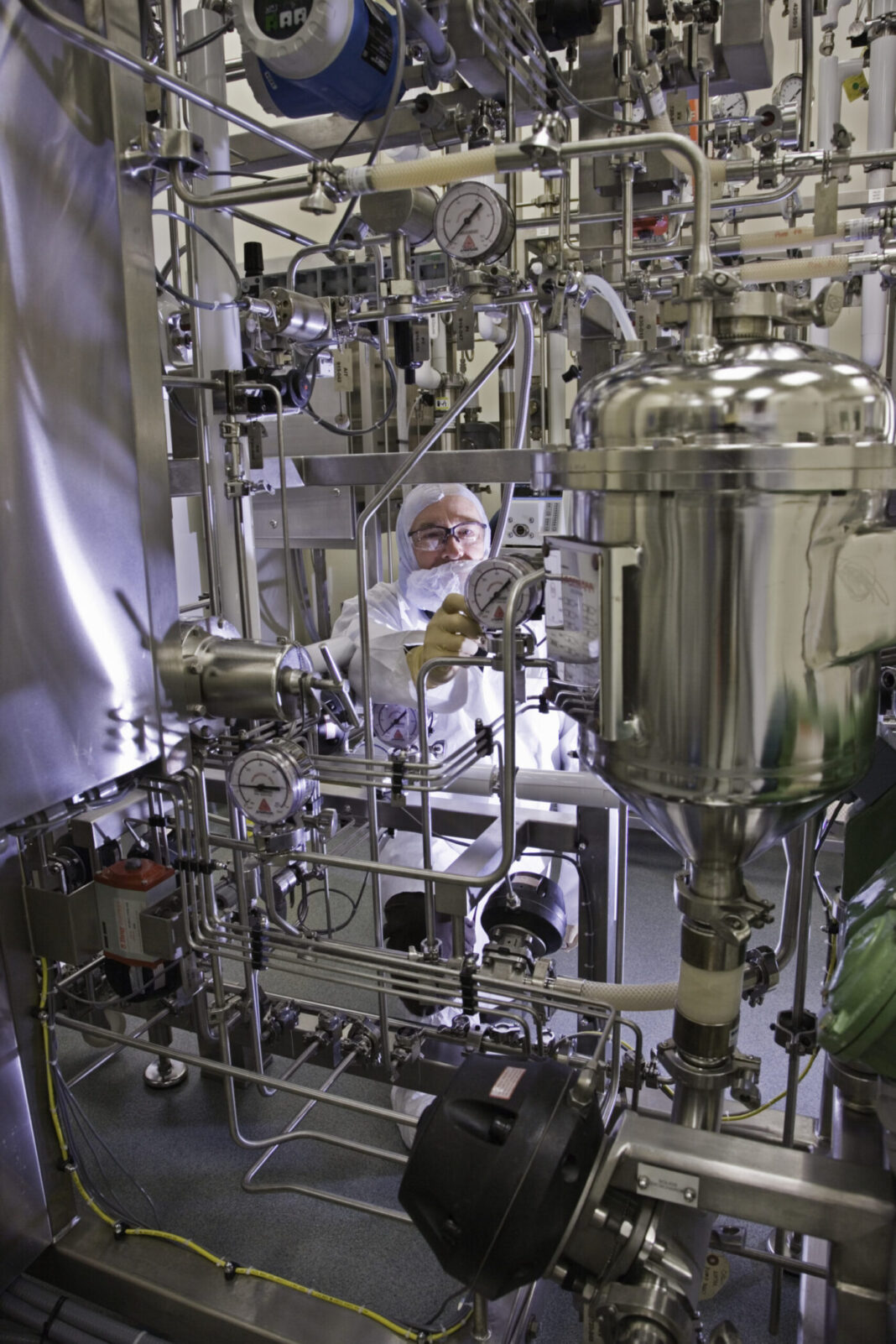 Scientist operating centrifugation skid, separating cells from bioreactor harvest