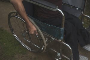 An anonymous polio survivor pushes the handrims of his wheelchair.