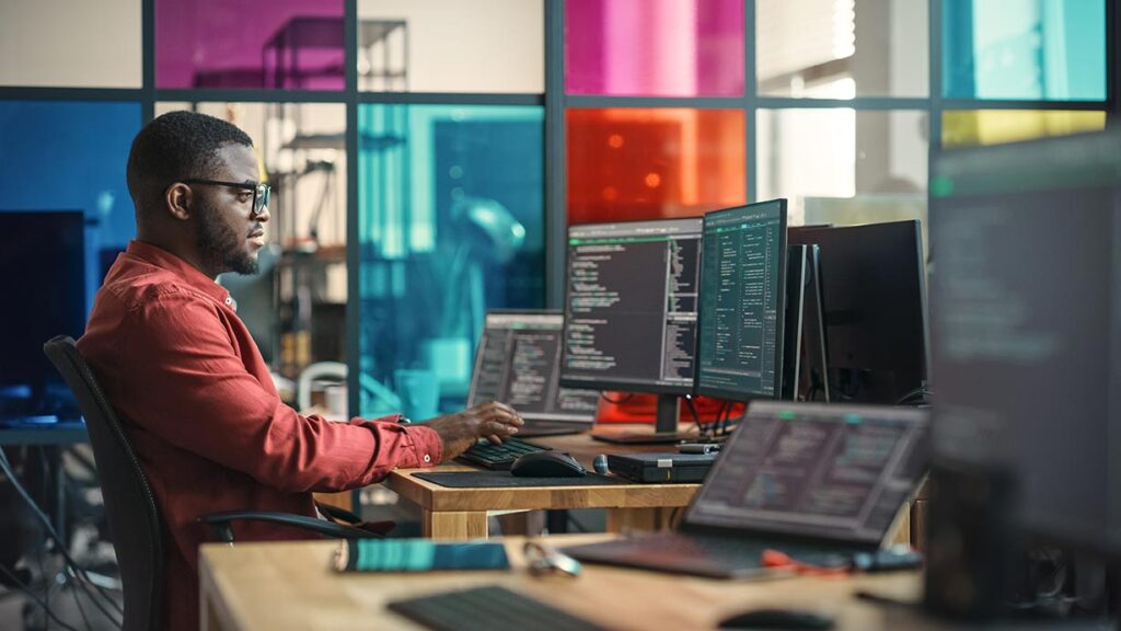 Man Writing Lines Of Code On Desktop Computer