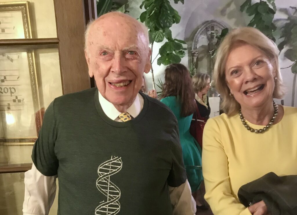 James Watson, PhD, sporting a double-helix T-shirt on his 90th birthday, as his wife Elizabeth looks on.