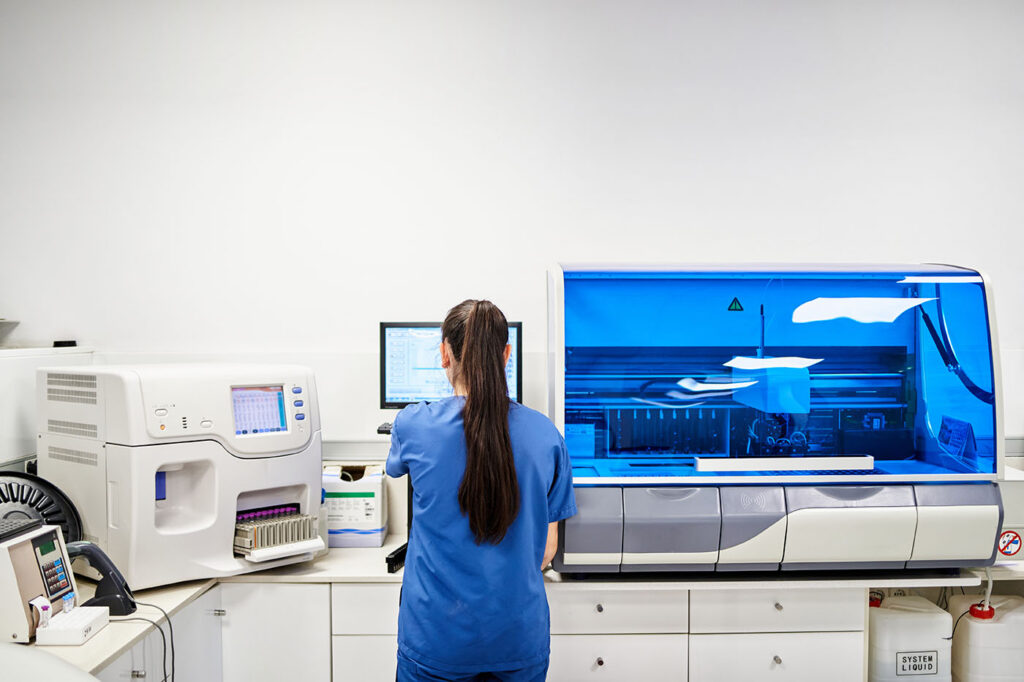 Rear view of a female worker using a computer in scrubs