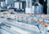 When Process Design Fails: 5 Common Planning Gaps That Create Downstream Purification Bottlenecks Advanced Bright Modern Pharmaceutical Factory. Medical Ampoule Production Line. Rows of Glass Vials with Orange Caps on Conveyor Belt. Vaccine Production Facility. Medication Manufacturing Process.