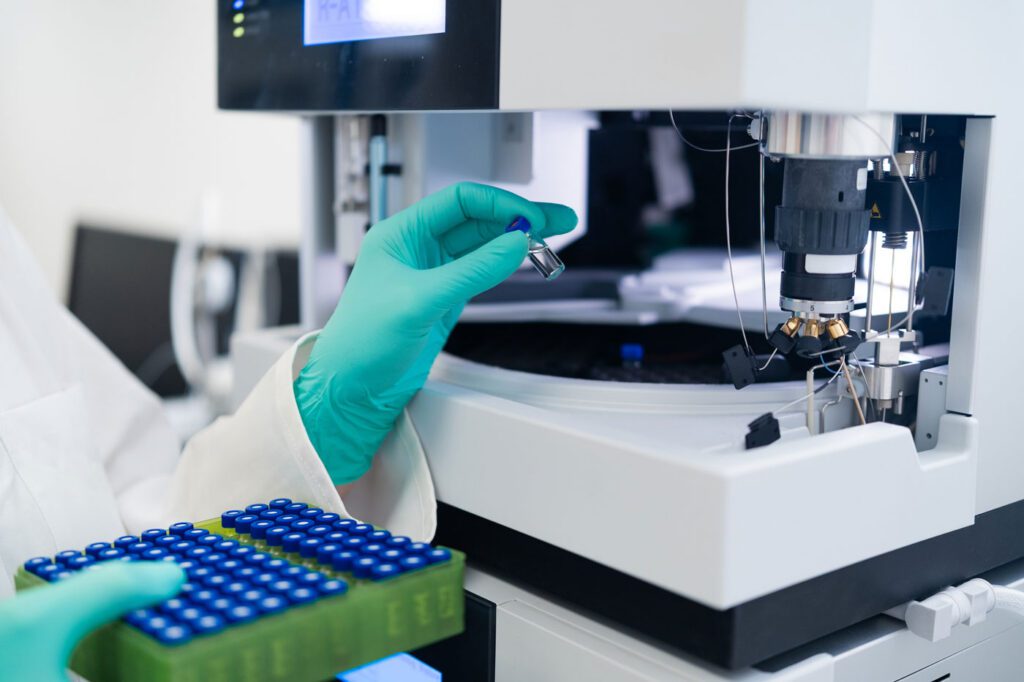 Close up of woman chemist operating HPLC autosampler for sample preparation